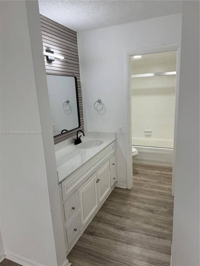 full bathroom featuring vanity, a textured ceiling, bathing tub / shower combination, hardwood / wood-style floors, and toilet