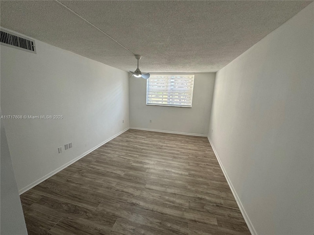 unfurnished room with a textured ceiling and dark wood-type flooring