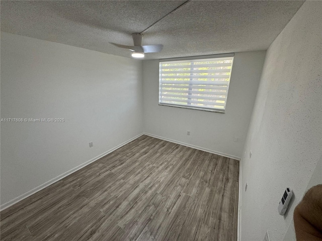 spare room with ceiling fan, a textured ceiling, and hardwood / wood-style flooring