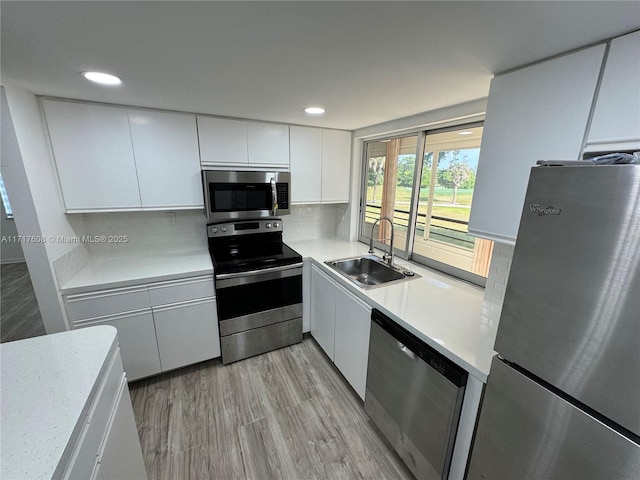 kitchen with white cabinets, appliances with stainless steel finishes, decorative backsplash, and sink