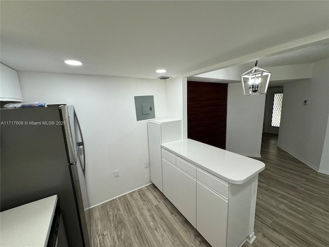 kitchen featuring white cabinetry, kitchen peninsula, stainless steel fridge, electric panel, and light hardwood / wood-style floors