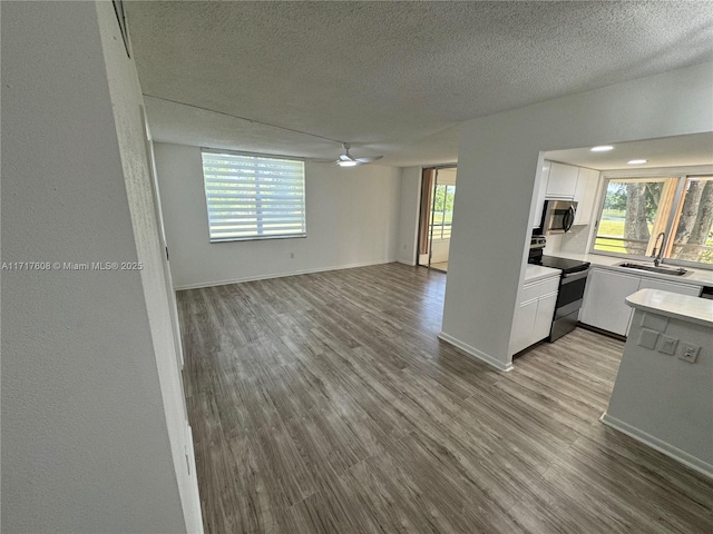 interior space featuring ceiling fan, light hardwood / wood-style floors, sink, and a textured ceiling