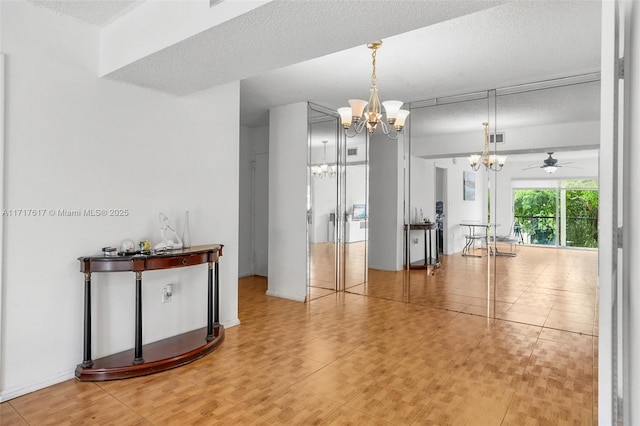 interior space featuring a textured ceiling and ceiling fan with notable chandelier