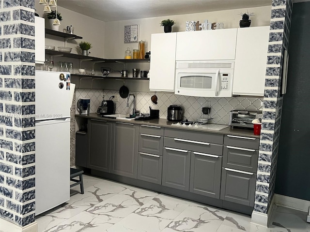 kitchen with backsplash, white cabinetry, white appliances, and sink