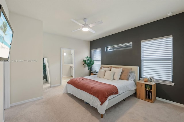 bedroom with light carpet, connected bathroom, multiple windows, and ceiling fan