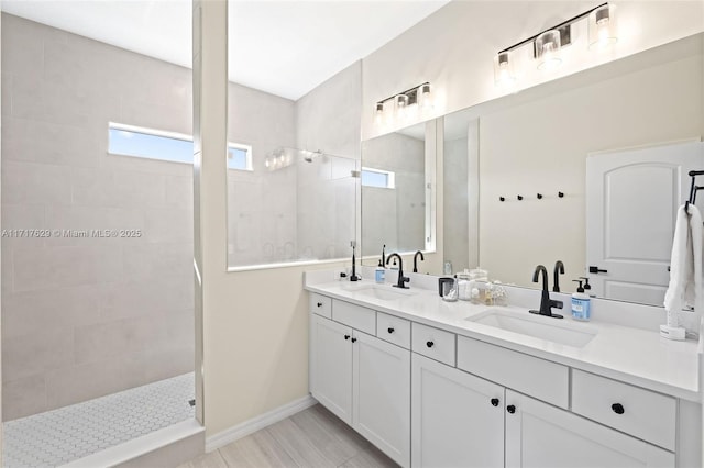 bathroom with a tile shower and vanity