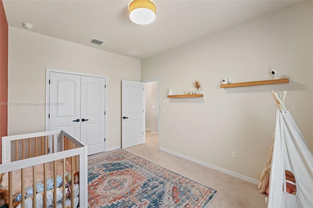 unfurnished bedroom featuring light colored carpet, a crib, and a closet