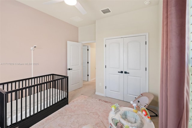 carpeted bedroom featuring ceiling fan, a crib, and a closet