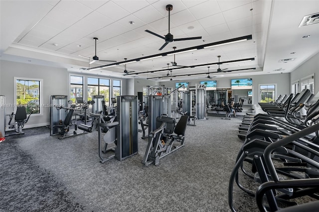 exercise room featuring a tray ceiling and ceiling fan