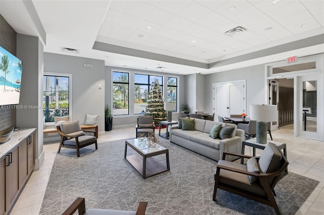 living room with light tile patterned floors and a raised ceiling