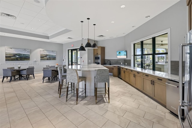 kitchen with tasteful backsplash, light stone countertops, sink, and hanging light fixtures