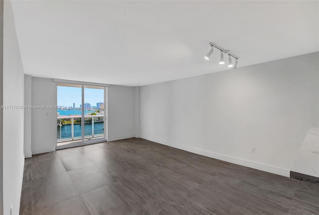 unfurnished room featuring rail lighting and a water view