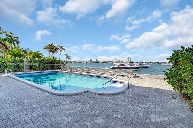 view of swimming pool featuring a water view and a patio area