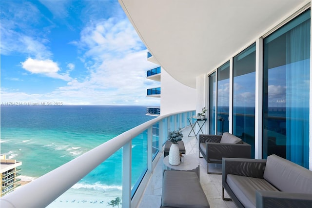 balcony featuring a view of the beach, an outdoor living space, and a water view