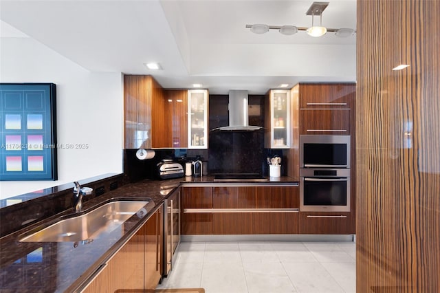 kitchen featuring sink, wall chimney exhaust hood, dark stone countertops, light tile patterned floors, and black cooktop