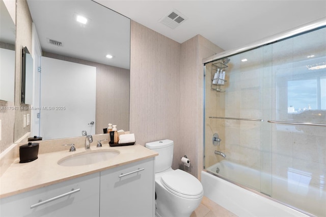 full bathroom featuring shower / bath combination with glass door, tile patterned flooring, vanity, and toilet