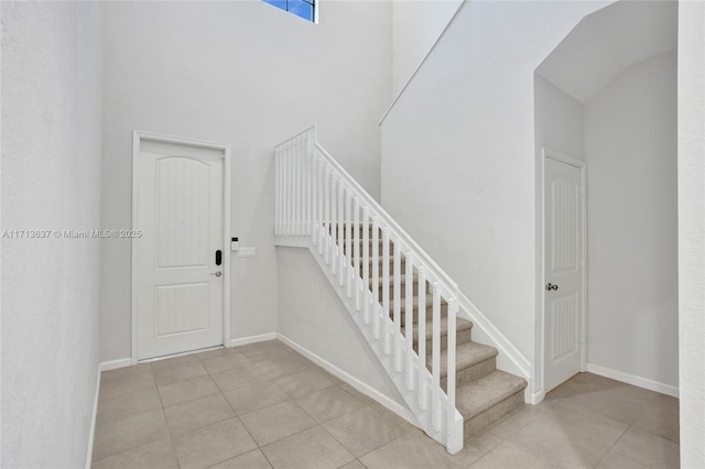 staircase featuring tile patterned flooring and a high ceiling