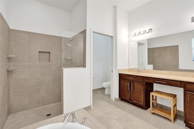 bathroom with a tile shower, tile patterned flooring, vanity, and toilet