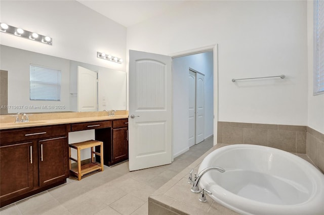 bathroom with tile patterned floors, tiled bath, and vanity