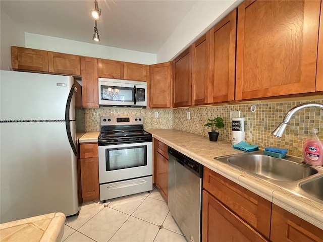 kitchen with tile countertops, decorative backsplash, sink, and stainless steel appliances