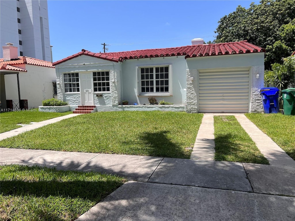 mediterranean / spanish home with a front yard and a garage