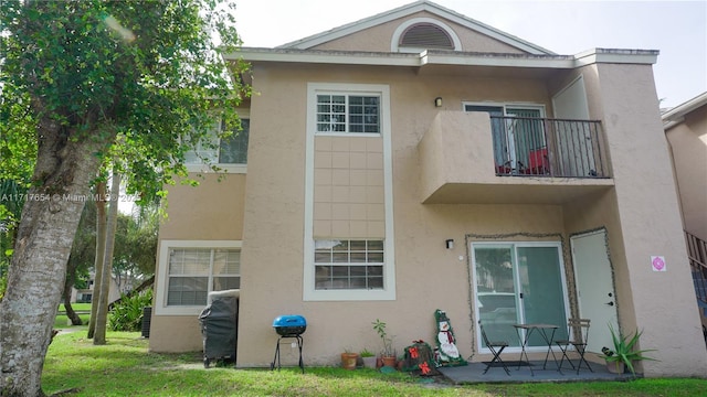 rear view of property featuring a balcony and a lawn