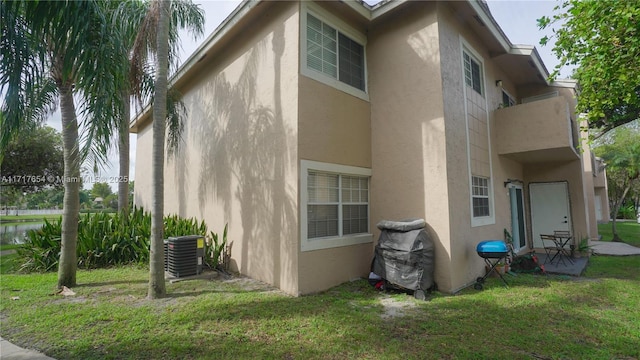 view of side of property featuring central AC and a lawn