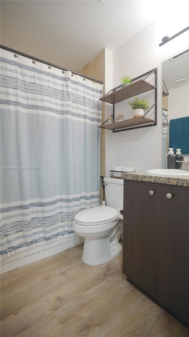 bathroom featuring a shower with curtain, vanity, hardwood / wood-style flooring, and toilet