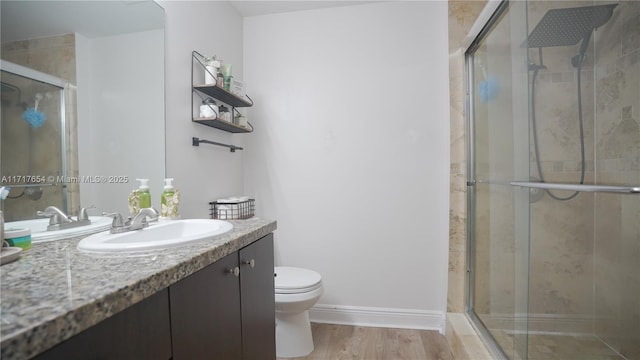 bathroom featuring vanity, wood-type flooring, a shower with shower door, and toilet