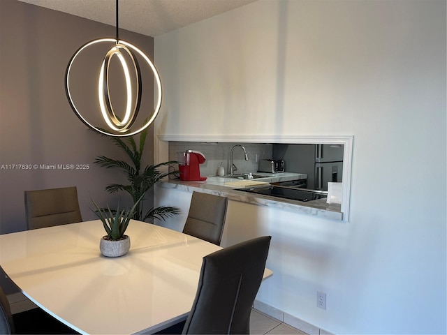 dining area with a textured ceiling, light tile patterned floors, and sink