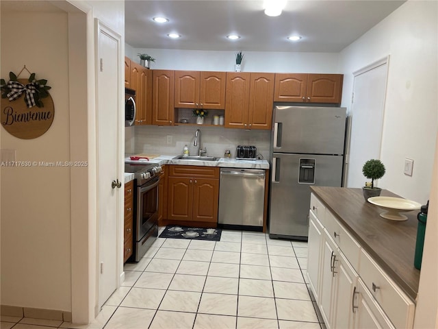 kitchen with backsplash, light tile patterned flooring, sink, and appliances with stainless steel finishes