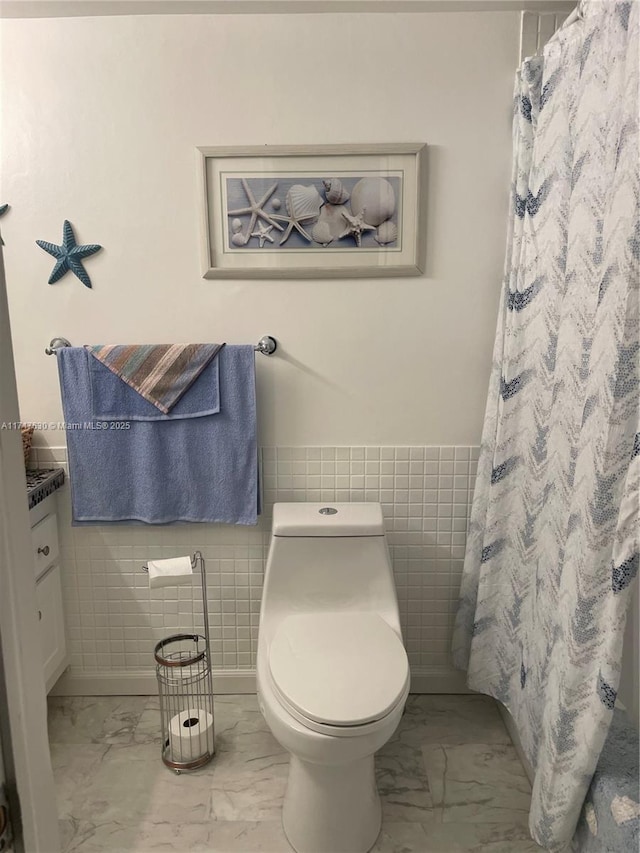 bathroom with vanity, a shower with shower curtain, tile walls, and toilet