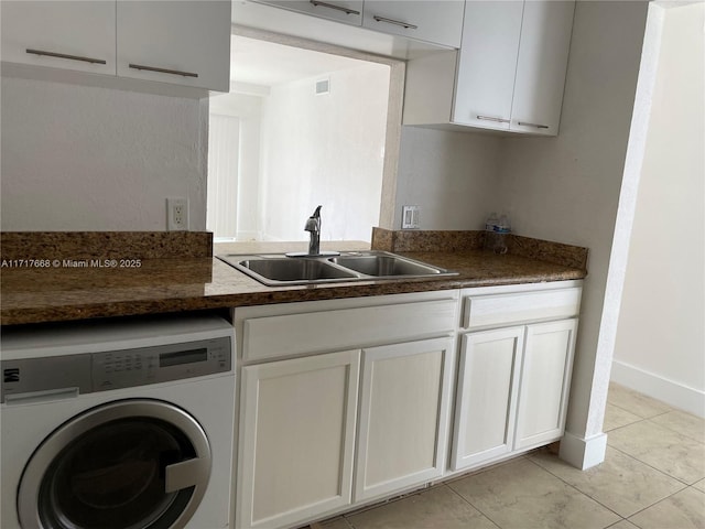 kitchen with white cabinets, light tile patterned flooring, washer / dryer, and sink