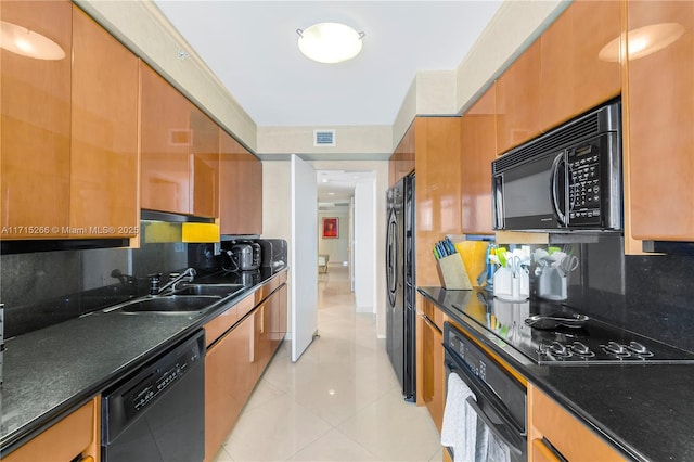 kitchen with backsplash, sink, light tile patterned floors, and black appliances