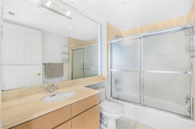 full bathroom featuring vanity, bath / shower combo with glass door, and toilet