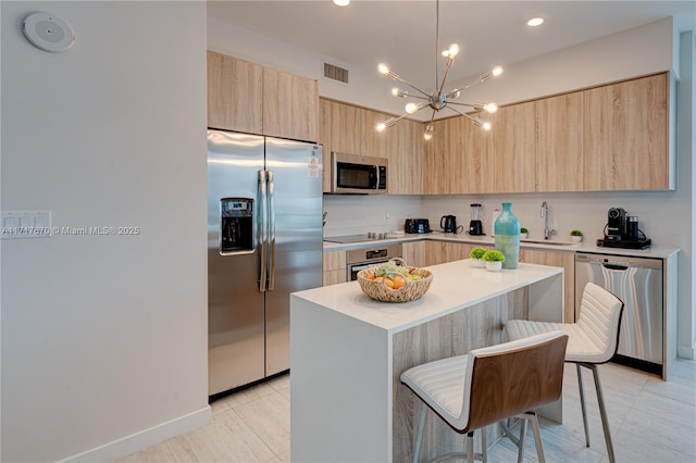 kitchen with appliances with stainless steel finishes, sink, light tile patterned floors, a kitchen island, and a breakfast bar area