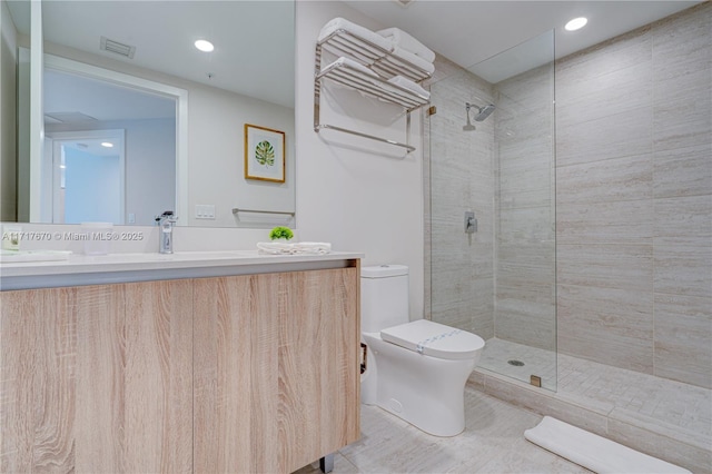 bathroom featuring tiled shower, vanity, and toilet