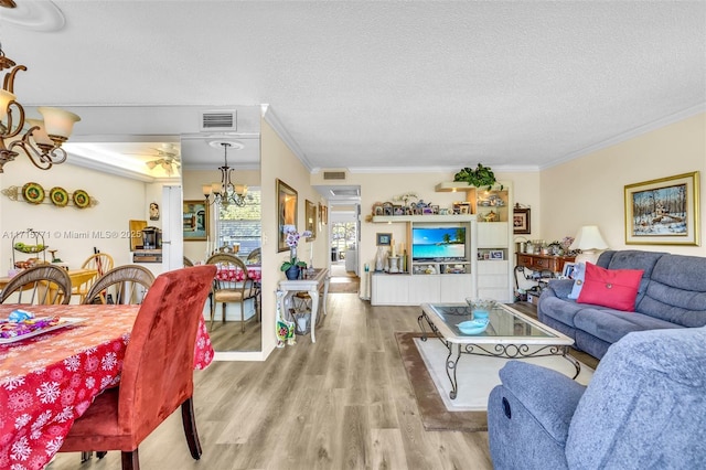 living room with hardwood / wood-style flooring, ceiling fan with notable chandelier, crown molding, and a textured ceiling