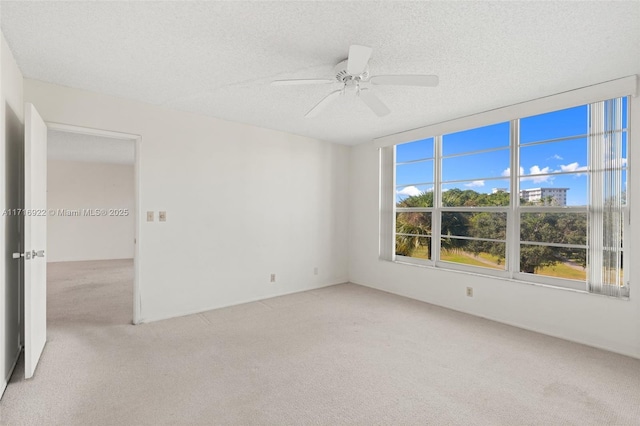 spare room featuring a textured ceiling, light colored carpet, and ceiling fan