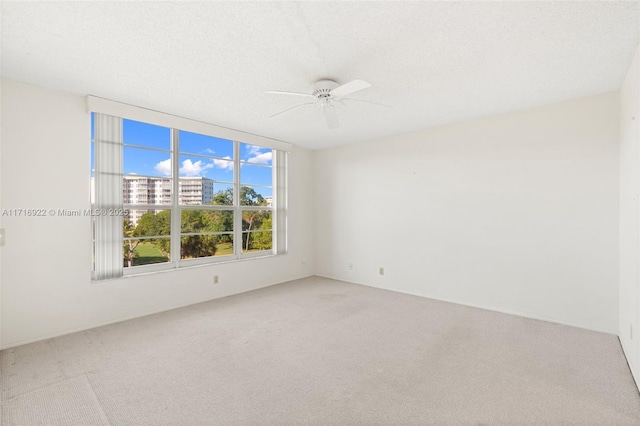 carpeted spare room featuring ceiling fan and a textured ceiling