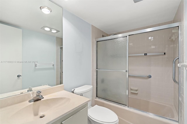 full bathroom with vanity, bath / shower combo with glass door, and toilet