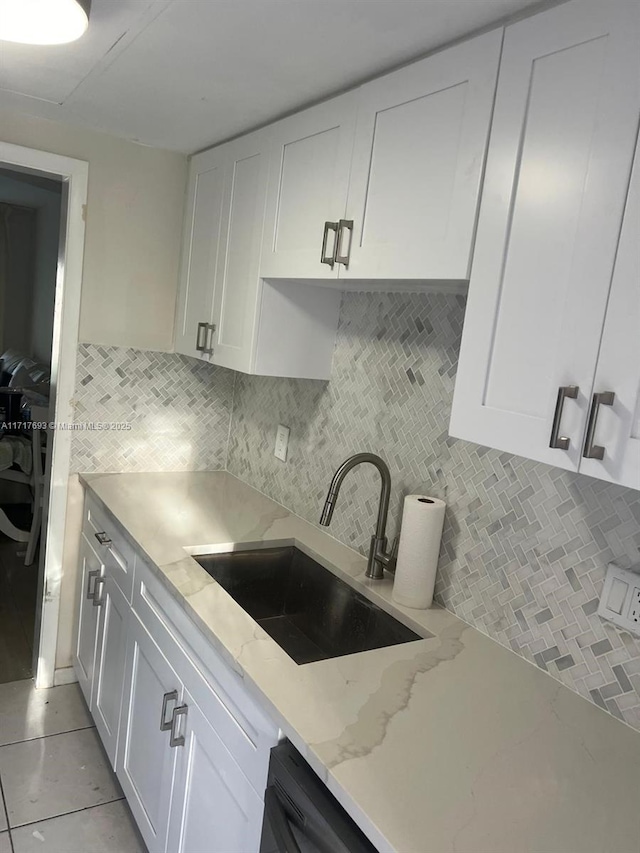 kitchen featuring white cabinets, light tile patterned floors, light stone counters, and sink