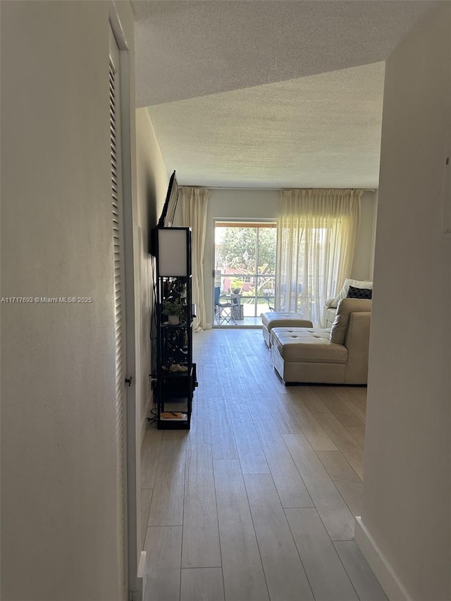 hall with a textured ceiling and light hardwood / wood-style flooring