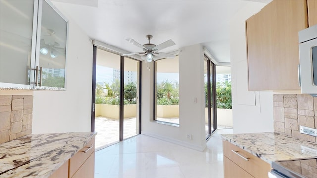 doorway to outside featuring ceiling fan and a wall of windows