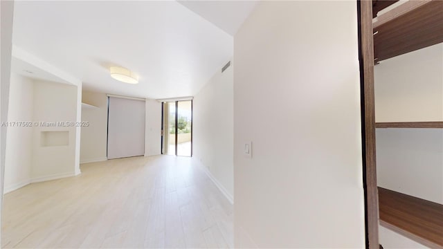 empty room with light wood-type flooring and a wall of windows