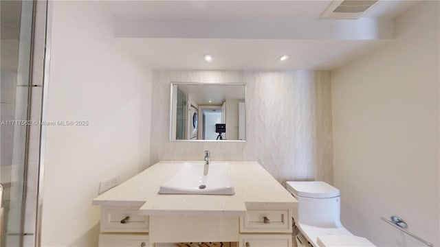 bathroom featuring vanity, toilet, and stacked washer / drying machine