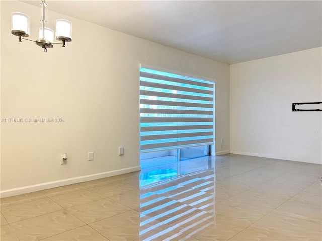 empty room with light tile patterned floors and a notable chandelier