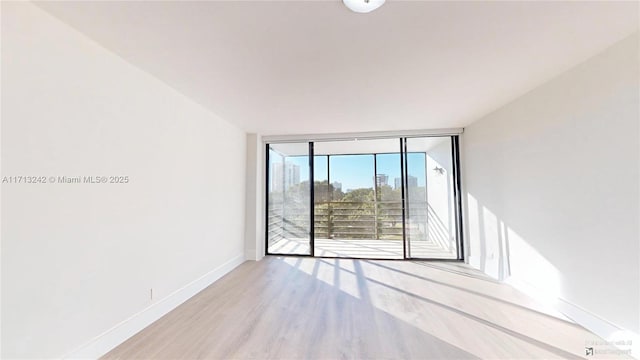 spare room featuring a wall of windows and light hardwood / wood-style floors