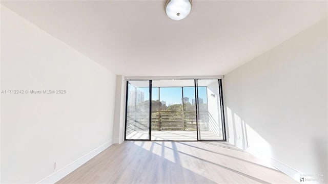 empty room with light wood-type flooring and a wall of windows