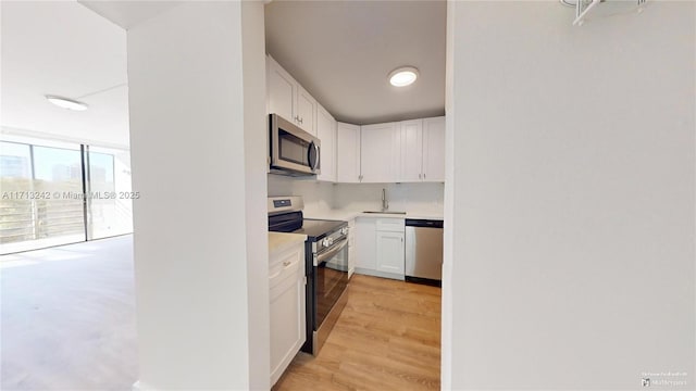 kitchen with white cabinetry, appliances with stainless steel finishes, sink, and light wood-type flooring